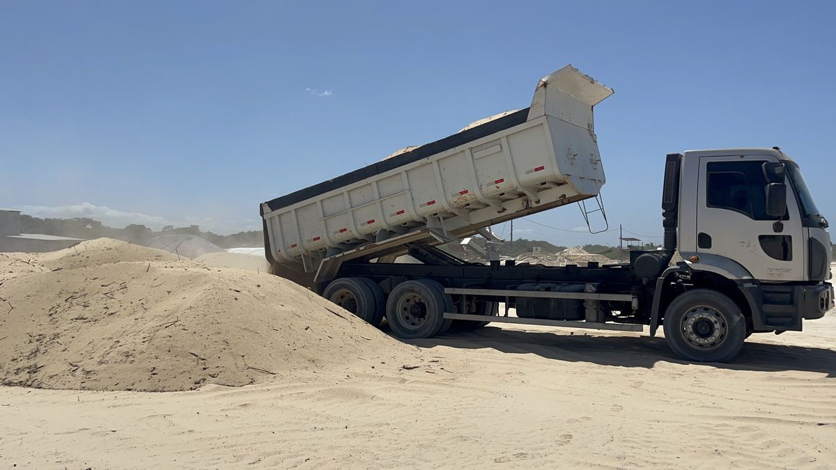 Caminhão basculante descarregando areia no estoque de matéria-prima
