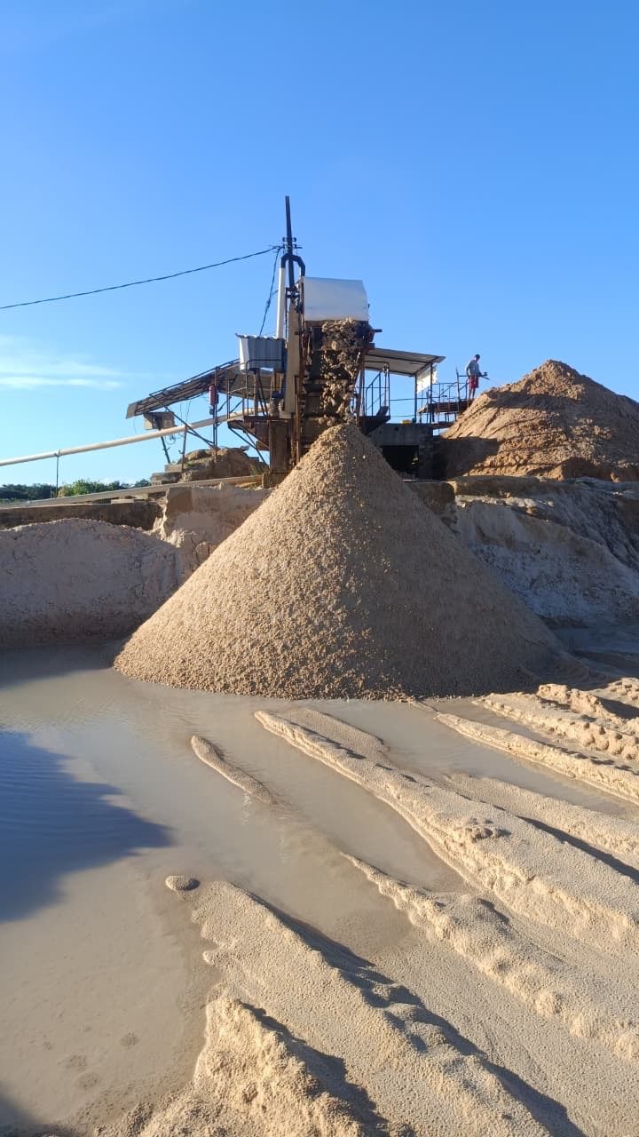 Planta de lavagem formando um monte cônico de areia, com uma pessoa no alto da estrutura