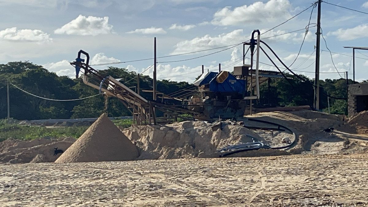 Planta de lavagem com hidrociclones, esteira e cone de areia sob céu azul