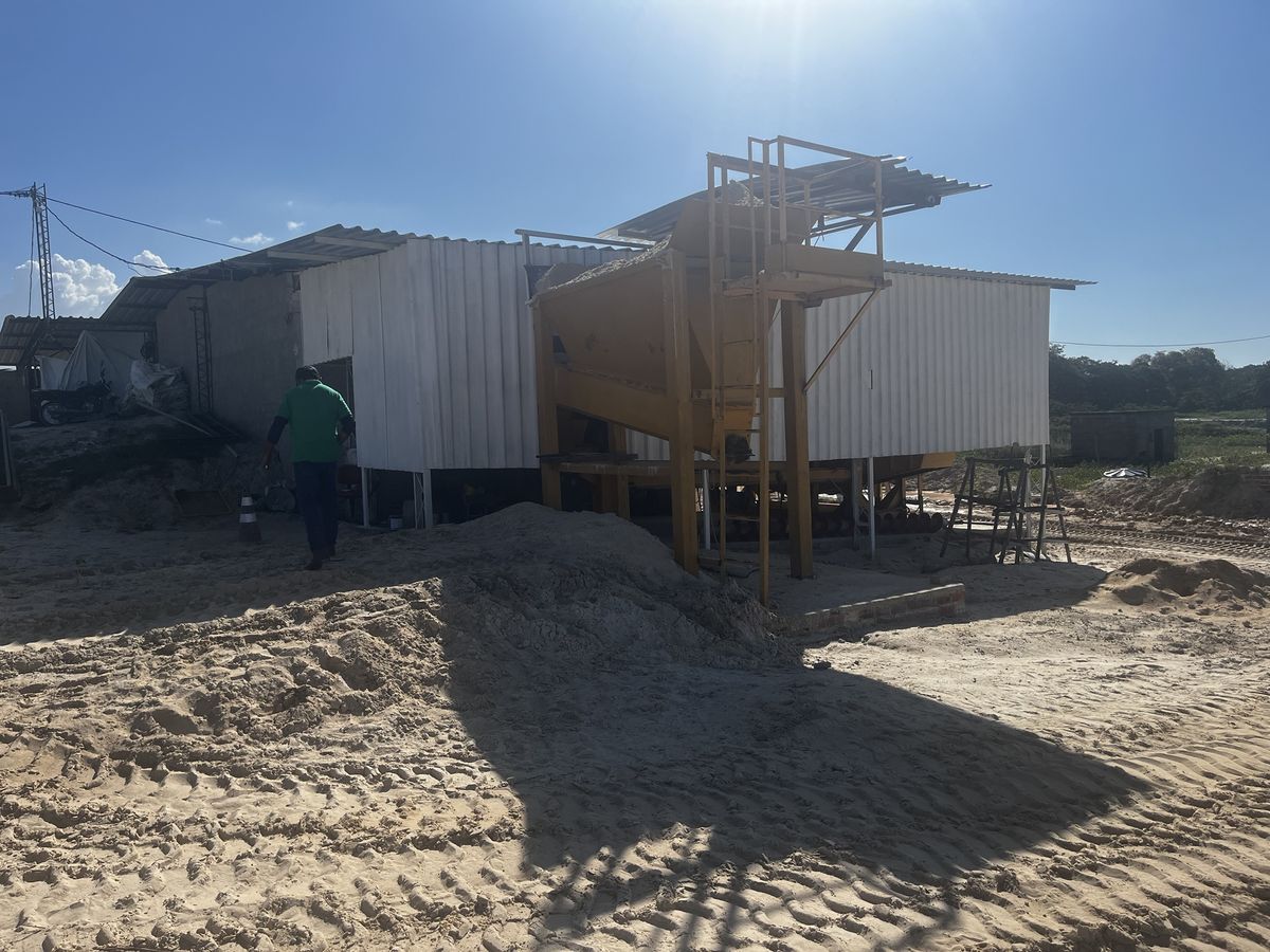Funcionário da APV ao lado da moega amarela que alimenta a linha de secagem