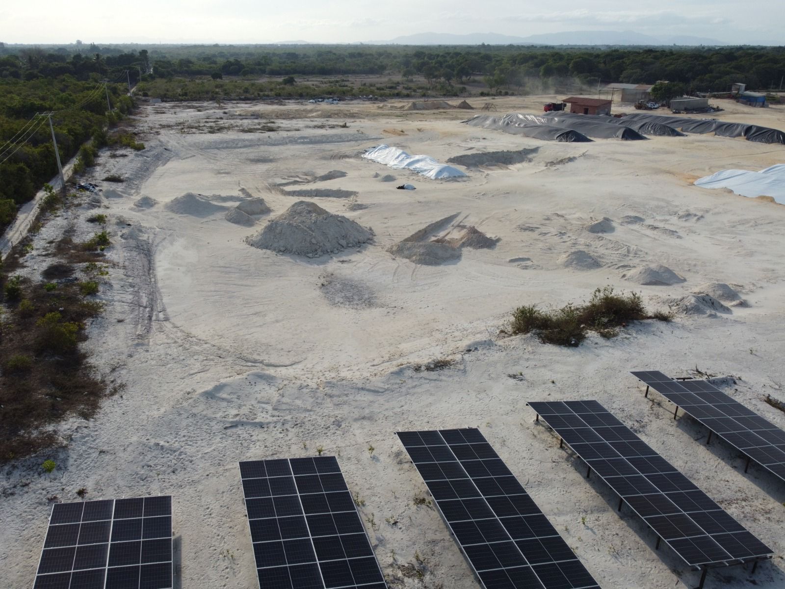 Vista aérea da usina solar em solo ao lado do pátio da planta